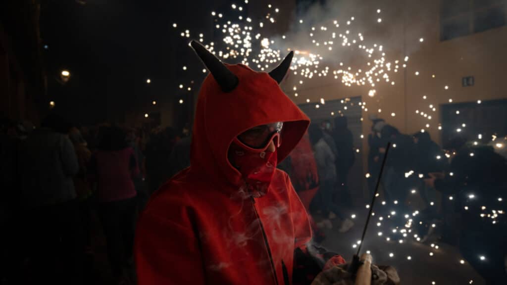 Close-up of a man dressed as a devil lighting a sparkler during the traditional Spanish festival,